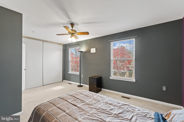 bedroom featuring light carpet, a closet, and ceiling fan