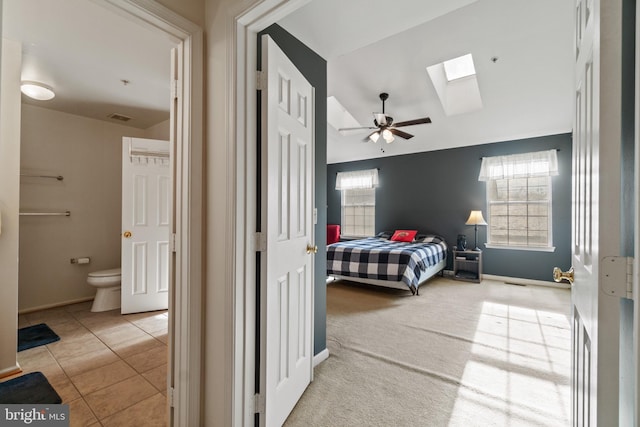 carpeted bedroom with connected bathroom, a skylight, and ceiling fan