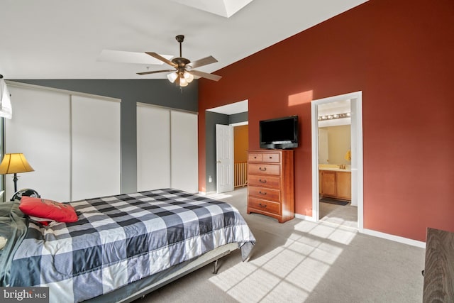 bedroom with light carpet, ensuite bath, two closets, ceiling fan, and lofted ceiling