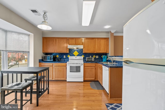 kitchen with tasteful backsplash, pendant lighting, white appliances, light wood-type flooring, and ornamental molding