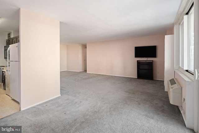 unfurnished living room with a wall mounted air conditioner and light colored carpet