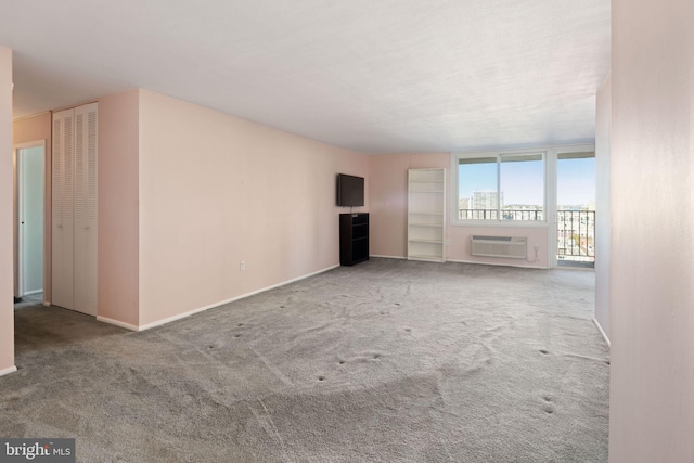 unfurnished living room with light colored carpet and a wall unit AC