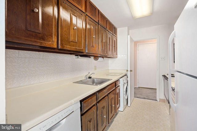 kitchen featuring decorative backsplash, white appliances, sink, and washer / clothes dryer