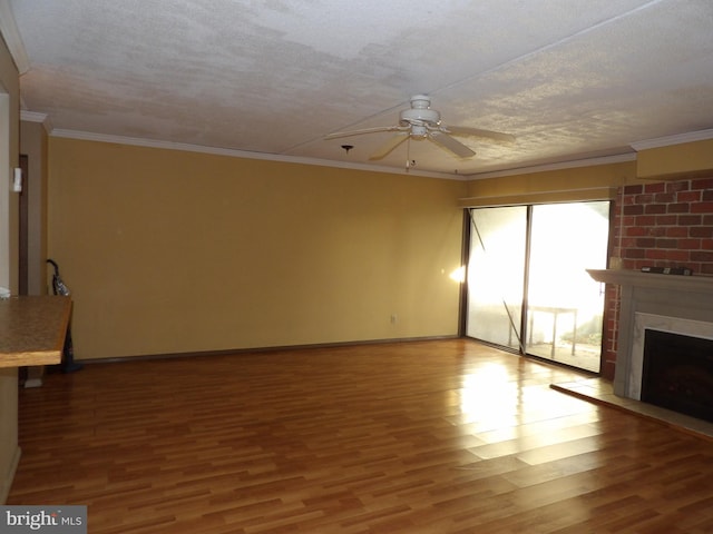 unfurnished living room with ornamental molding, a textured ceiling, ceiling fan, wood-type flooring, and a fireplace