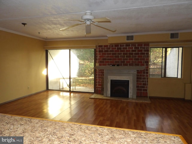 unfurnished living room with crown molding, a fireplace, a textured ceiling, and hardwood / wood-style flooring