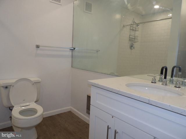 bathroom featuring tiled shower, hardwood / wood-style floors, vanity, and toilet