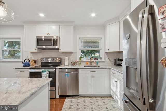 kitchen featuring pendant lighting, sink, tasteful backsplash, white cabinetry, and stainless steel appliances