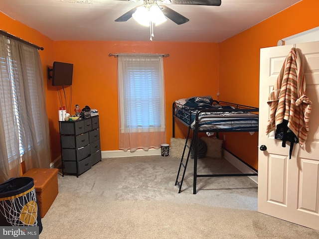 carpeted bedroom featuring multiple windows and ceiling fan