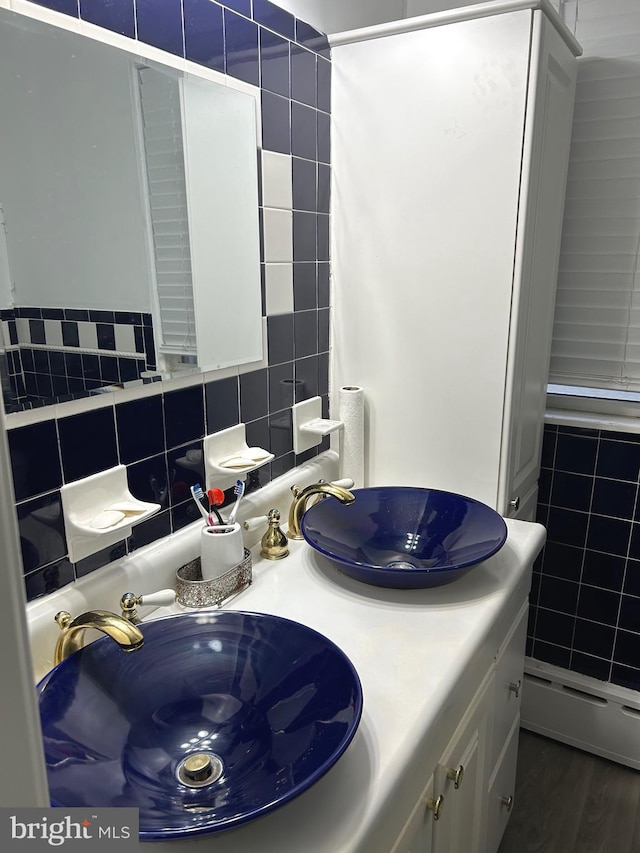 bathroom with baseboard heating, tasteful backsplash, vanity, tile walls, and hardwood / wood-style flooring