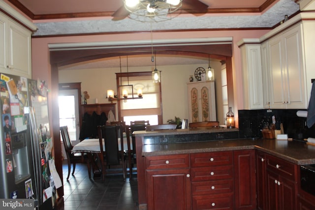 kitchen featuring tasteful backsplash, stainless steel fridge with ice dispenser, dark tile patterned floors, pendant lighting, and ceiling fan with notable chandelier