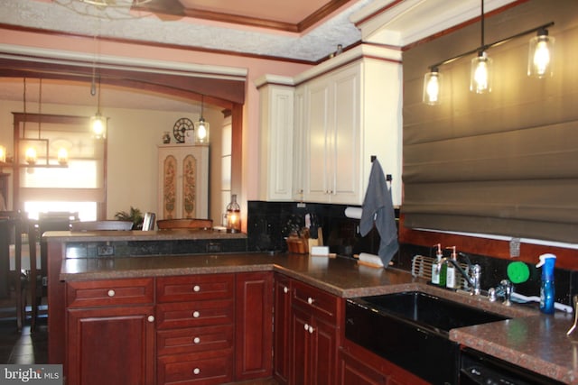 kitchen featuring sink, decorative light fixtures, crown molding, and backsplash