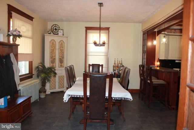 tiled dining room with radiator heating unit and a textured ceiling