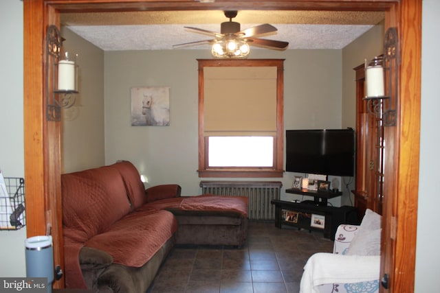 living room with ceiling fan, radiator heating unit, dark tile patterned flooring, and a textured ceiling