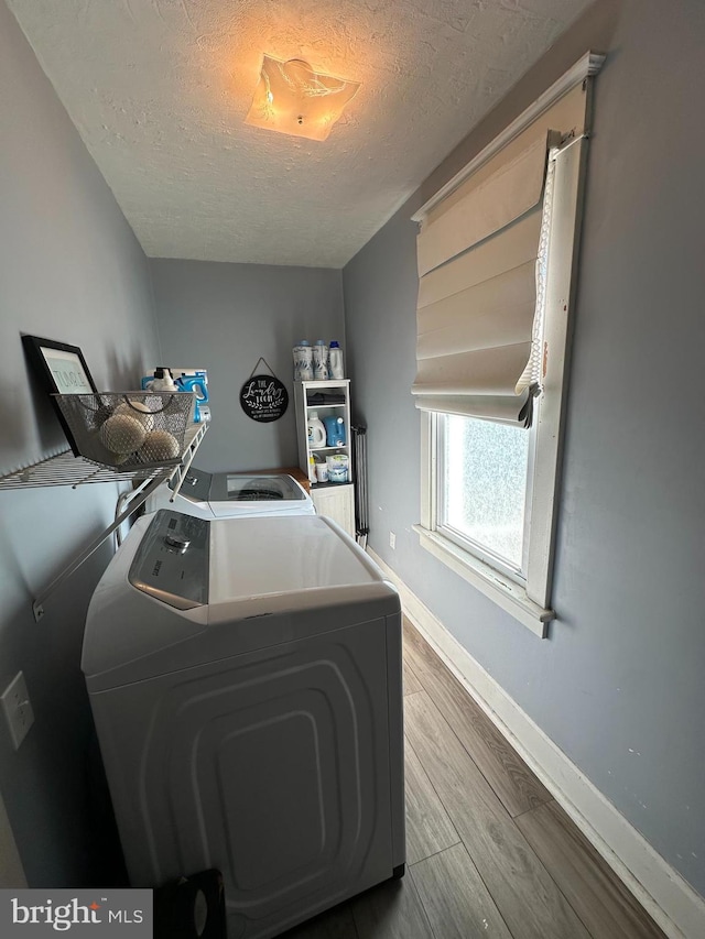 washroom with hardwood / wood-style floors, a textured ceiling, and washer and clothes dryer