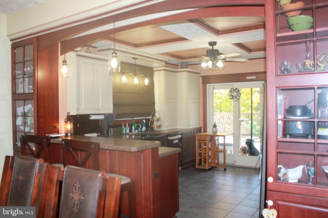 kitchen with coffered ceiling, ceiling fan, beamed ceiling, decorative light fixtures, and kitchen peninsula