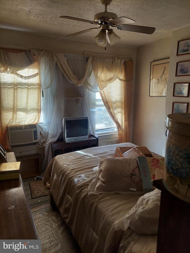 bedroom featuring hardwood / wood-style flooring, ceiling fan, cooling unit, and a textured ceiling