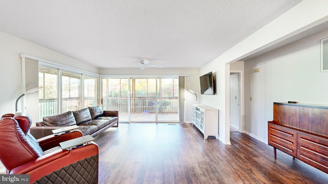 living room featuring dark hardwood / wood-style floors, ceiling fan, and a textured ceiling