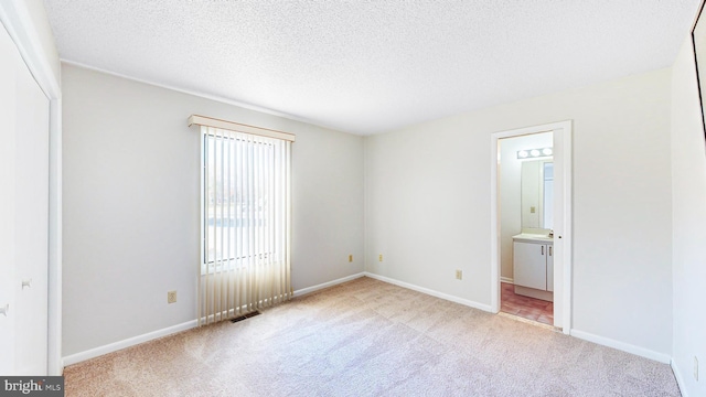 33945 Middleton Cir Unit 1, Lewes, DE 19958 - unfurnished bedroom with carpet flooring, a textured ceiling, baseboards, and connected bathroom