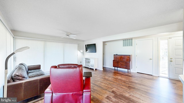 living room featuring dark hardwood / wood-style floors, ceiling fan, and a textured ceiling