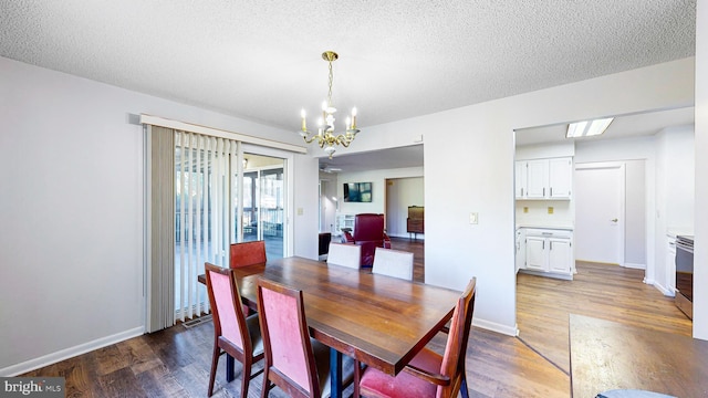 dining room with a textured ceiling, dark hardwood / wood-style floors, and an inviting chandelier