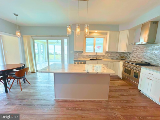 kitchen with light stone countertops, double oven range, a center island, and wall chimney exhaust hood