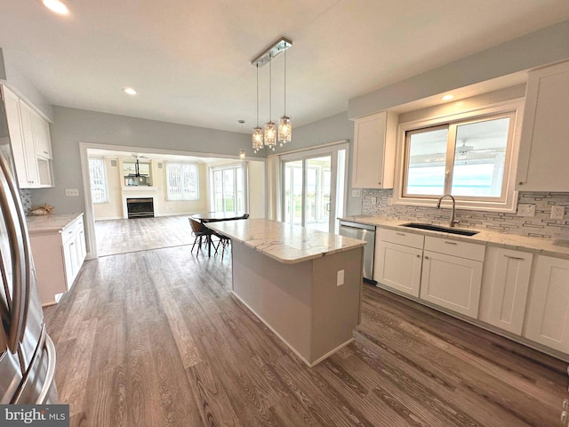 kitchen with dark hardwood / wood-style floors, a kitchen island, stainless steel dishwasher, sink, and white cabinets