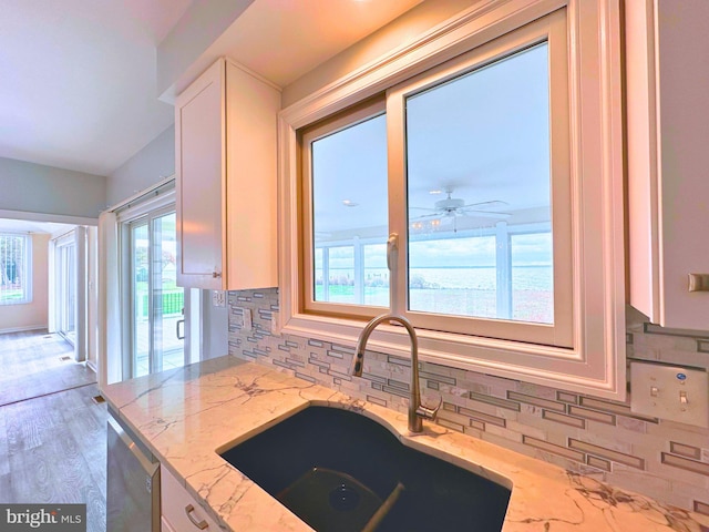 kitchen featuring white cabinets, ceiling fan, sink, light stone counters, and stainless steel dishwasher