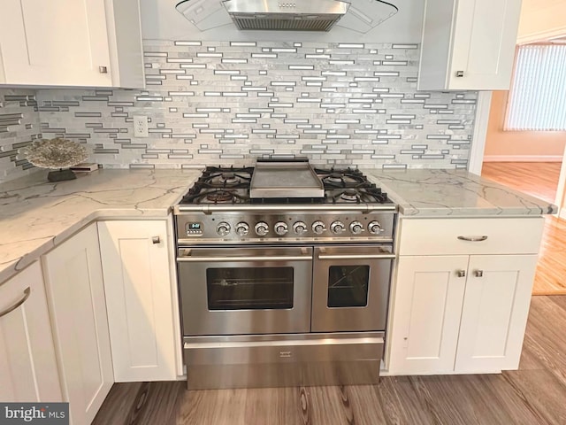 kitchen with double oven range, decorative backsplash, light stone counters, and white cabinetry