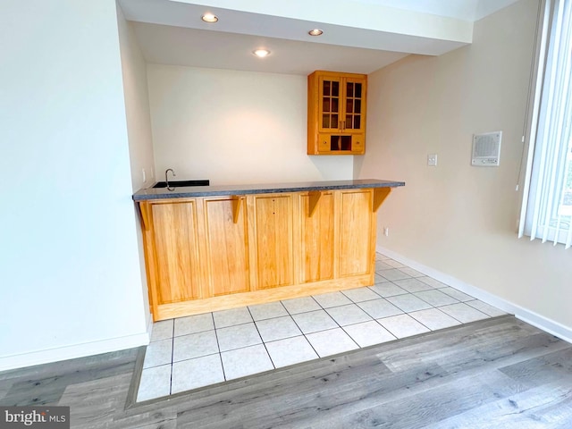 kitchen with light hardwood / wood-style flooring, kitchen peninsula, and a breakfast bar