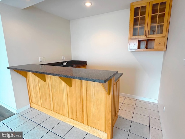 kitchen featuring a breakfast bar, kitchen peninsula, and light tile patterned floors