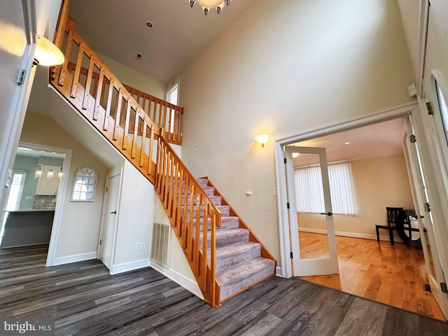 stairs with hardwood / wood-style flooring and a high ceiling