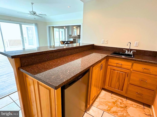 kitchen with kitchen peninsula, ceiling fan, dark stone countertops, stainless steel dishwasher, and sink