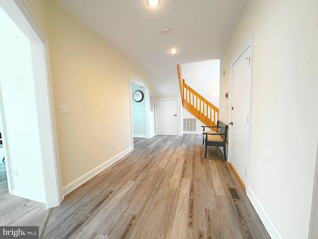 hall featuring lofted ceiling and light hardwood / wood-style floors