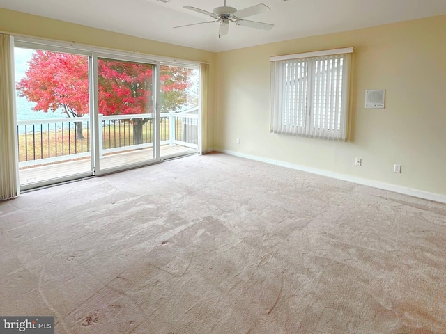 unfurnished room featuring ceiling fan, light colored carpet, and a water view