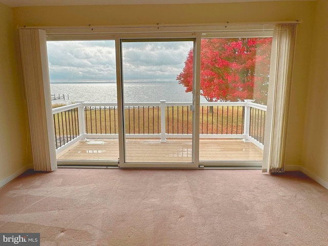 doorway with plenty of natural light, a water view, and carpet flooring