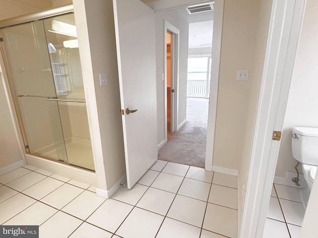 bathroom with toilet, tile patterned flooring, and a shower with shower door