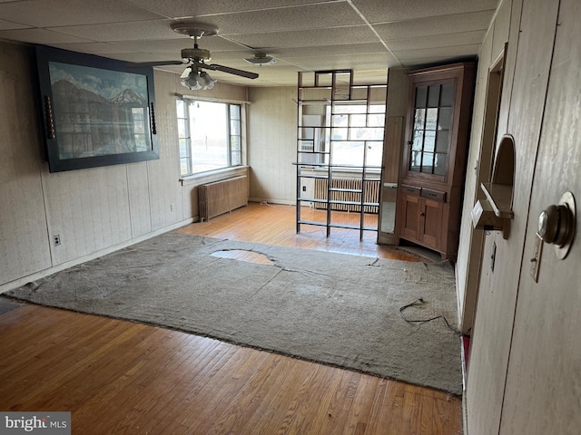 interior space featuring a paneled ceiling, light hardwood / wood-style floors, radiator, and ceiling fan