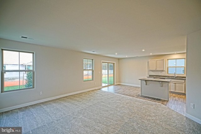 unfurnished living room with light hardwood / wood-style floors and sink