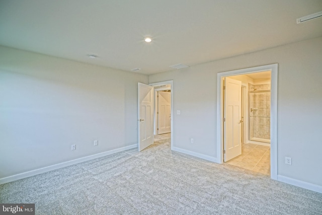 unfurnished bedroom featuring connected bathroom and light colored carpet