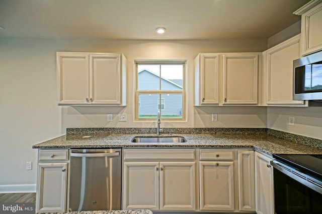 kitchen featuring sink, appliances with stainless steel finishes, dark hardwood / wood-style flooring, and dark stone countertops