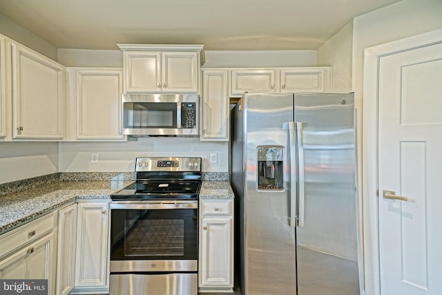 kitchen featuring light stone counters, white cabinets, and stainless steel appliances