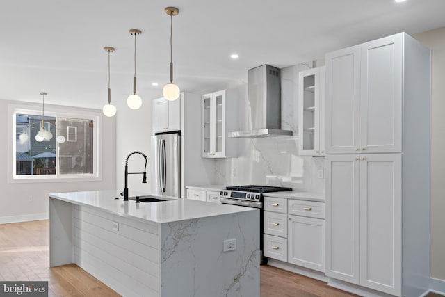 kitchen featuring pendant lighting, wall chimney exhaust hood, white cabinetry, and stainless steel appliances