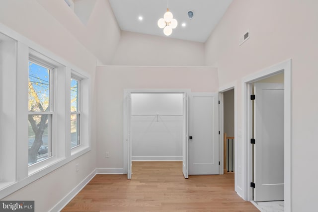 interior space featuring an inviting chandelier, light hardwood / wood-style floors, and high vaulted ceiling