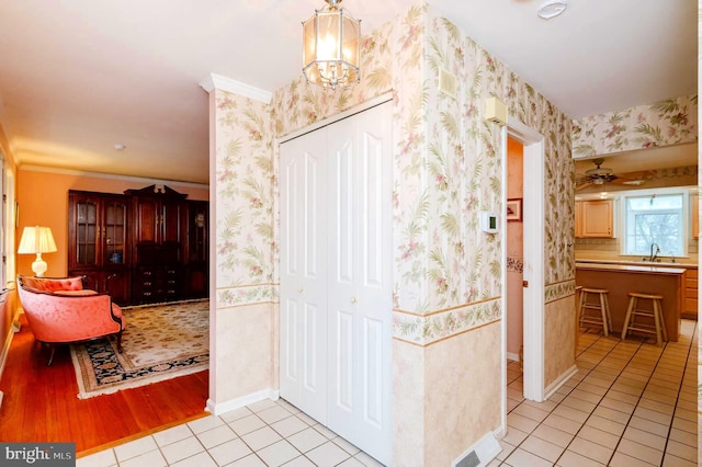 interior space with ceiling fan with notable chandelier, sink, light tile patterned floors, and crown molding