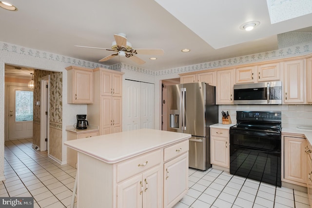 kitchen featuring a center island, a skylight, ceiling fan, light tile patterned floors, and appliances with stainless steel finishes