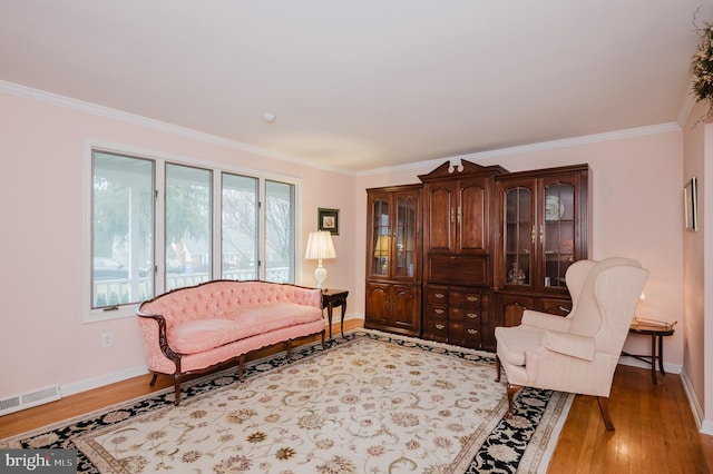 living area with light hardwood / wood-style flooring and ornamental molding