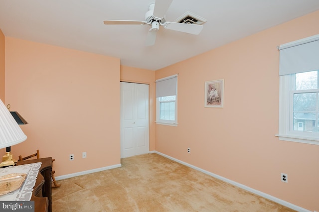 unfurnished bedroom featuring multiple windows, a closet, ceiling fan, and light colored carpet