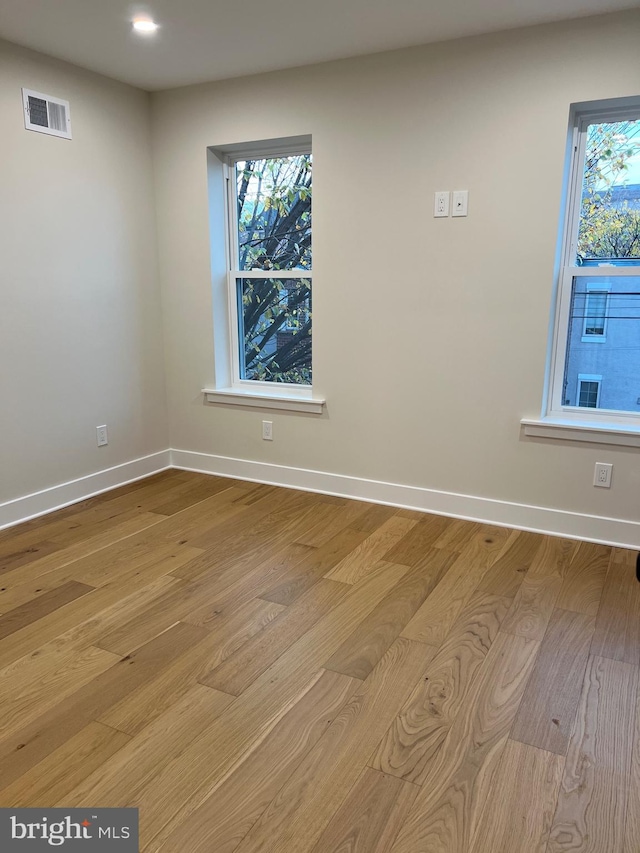 unfurnished room with a healthy amount of sunlight and light hardwood / wood-style floors