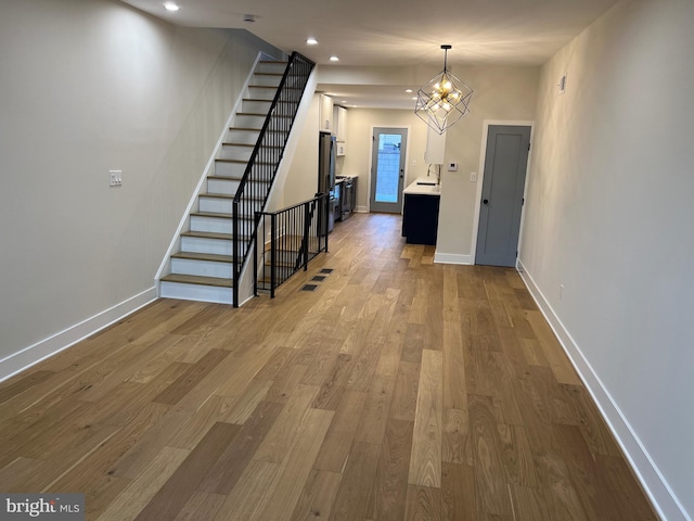 corridor with hardwood / wood-style floors and an inviting chandelier