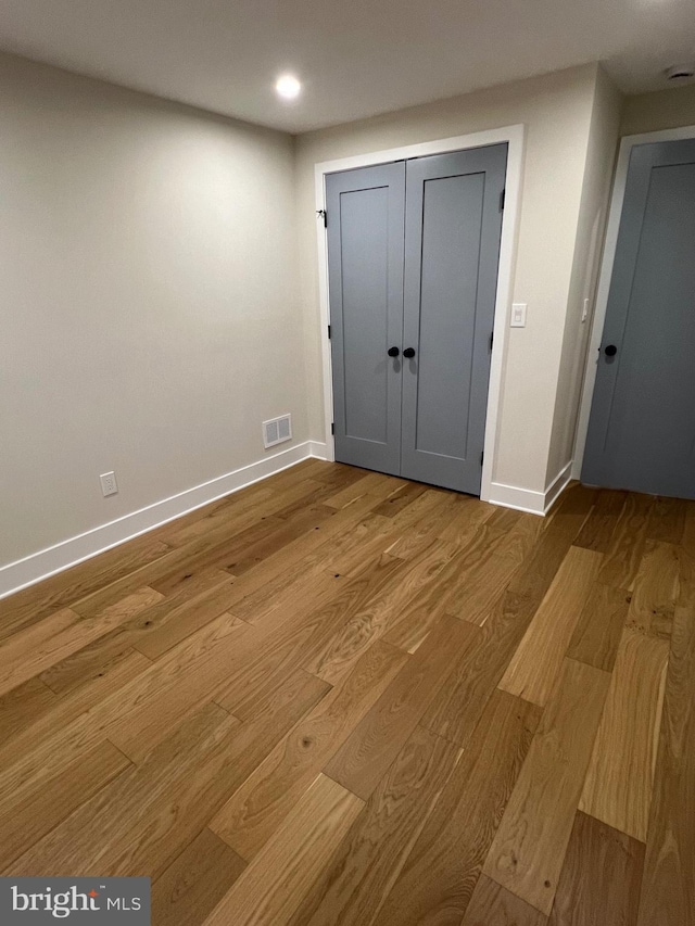 unfurnished bedroom with light wood-type flooring and a closet